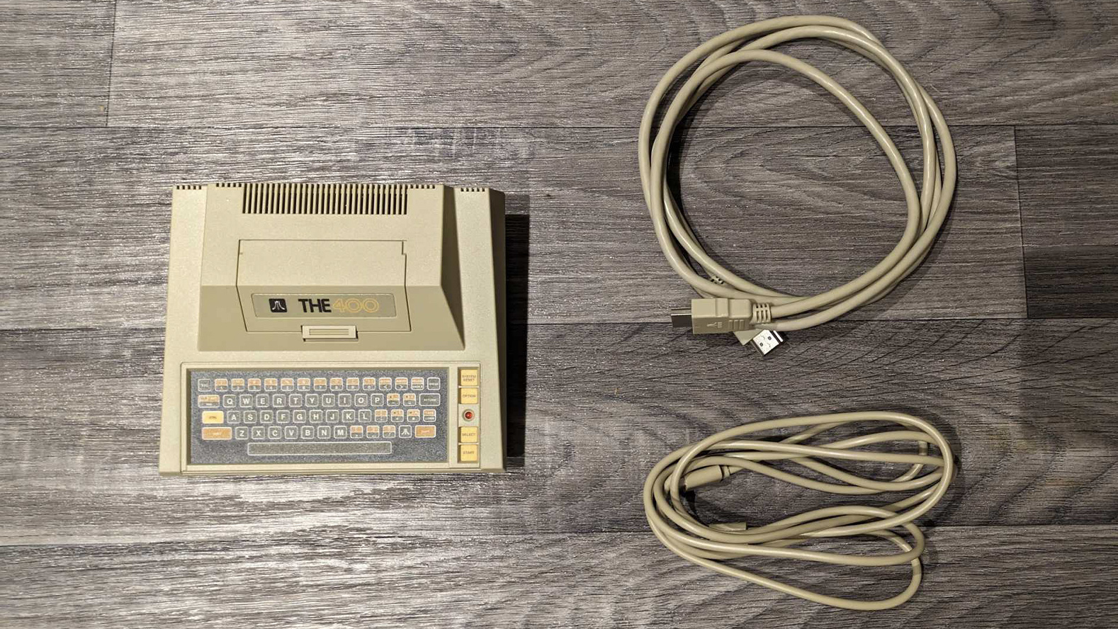 Atari 400 Mini review; a retro console with cables on a wooden floor