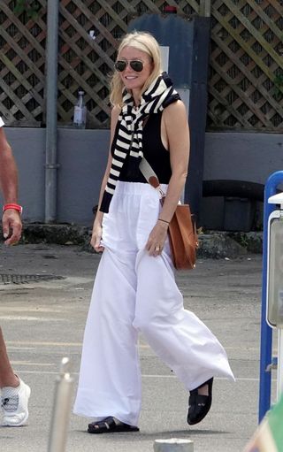 Gwyneth Paltrow walks on to a yacht in Capri with white linen pants and a rare hermes bag