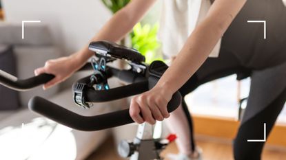 Lower half view of woman on an exercise bike grasping handlebars and cycling, representing the link between cycling and pelvic floor issues