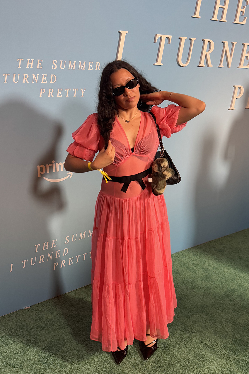 a woman wearing a pink sheer dress, and black pointed-toe shoes