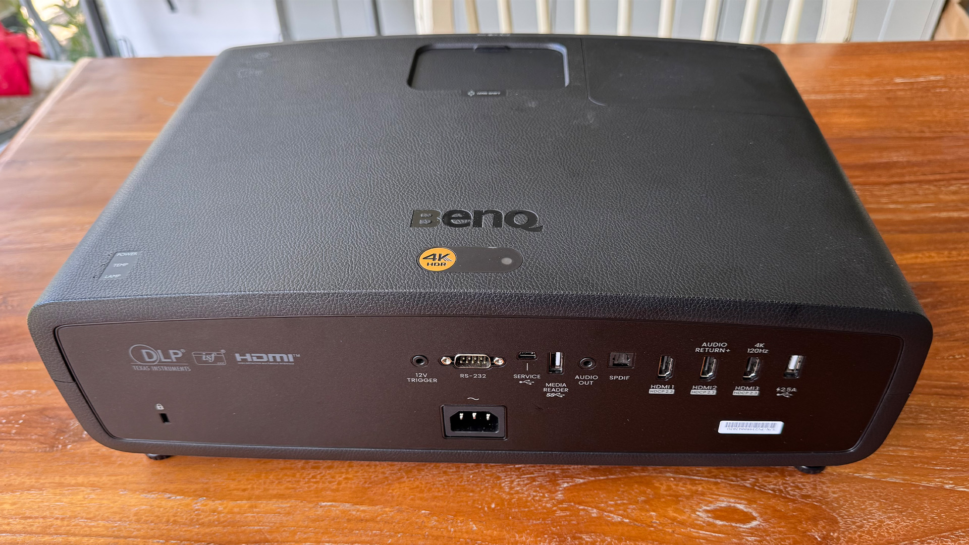 The BenQ W2720i projector, pictured on a wooden table in a living room