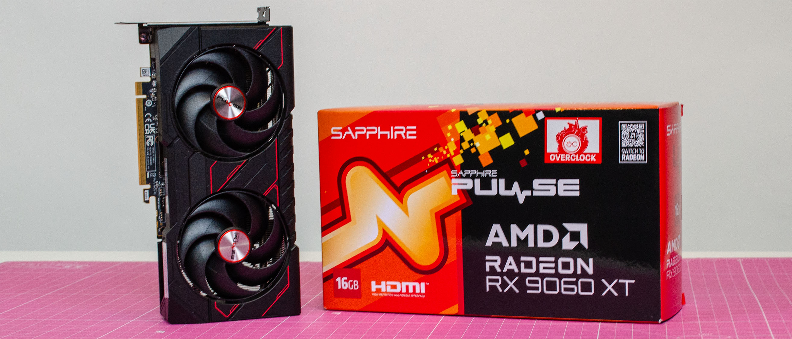 An AMD Radeon RX 9060 XT next to its retail packaging on a table