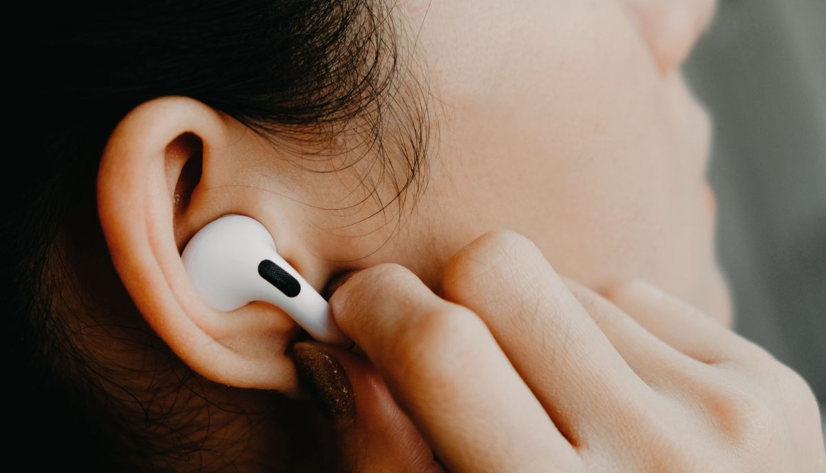 AirPods Pro in woman&#039;s ear, as she pinches the controls