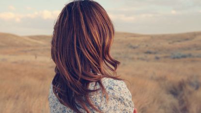 Woman with red hair wearing a floral dress staring into the distance