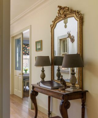 Hallway with French style wooden table and ornate framed mirror on neutral wall