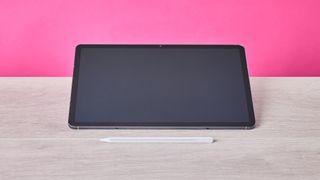 Front view of Samsung Galaxy Tab S11 and S Pen, on a desk with pink wall in background