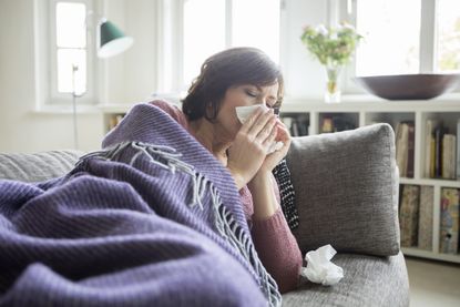 Woman sneezing with new symptoms of Covid-19