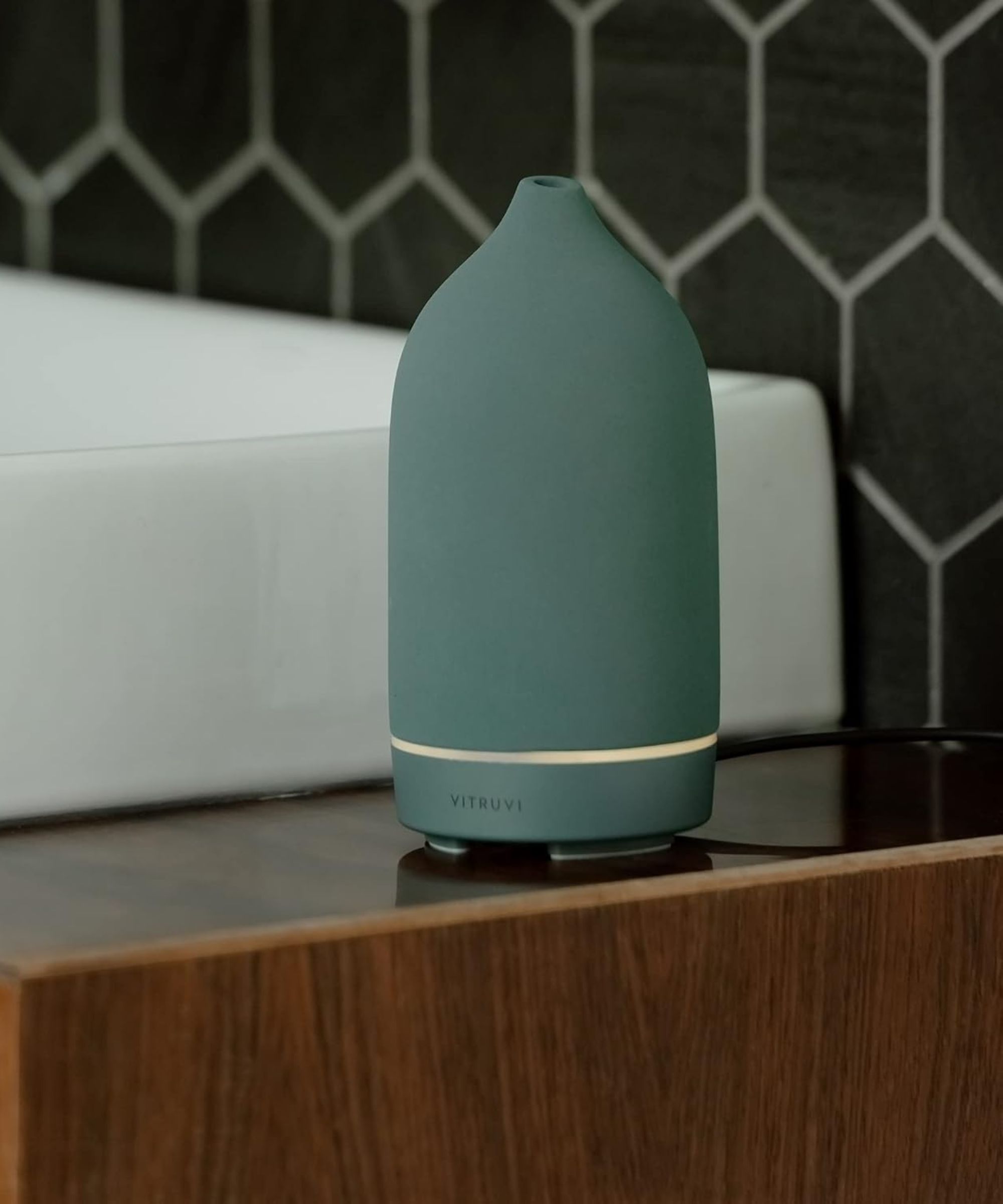 Vitruvi Sea on a wooden counter with a white sink and black tiles behind