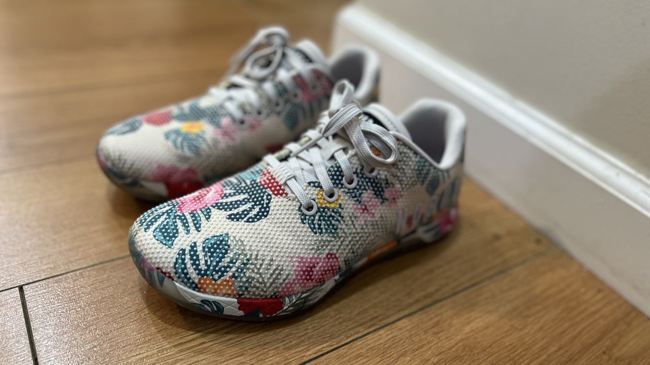 NoBull Outwork training shoes with tropical print resting on a wooden floor.