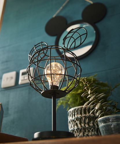 room with black mickey mouse on wall and plant in pot