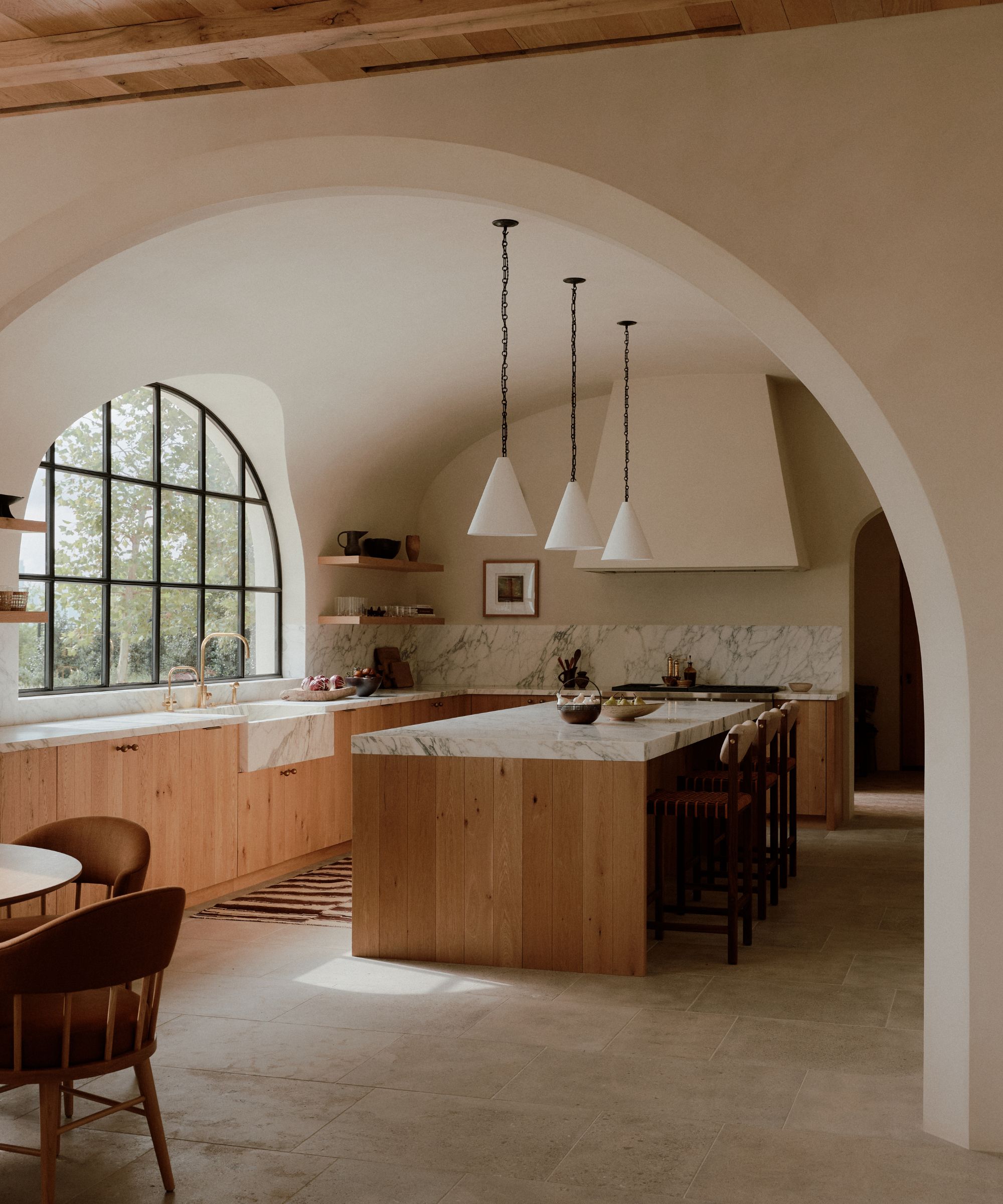 A wooden kitchen with plaster walls and marble countertops