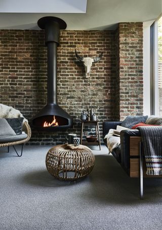 A living room with exposed brick wall, modern black fireplace, and bull wall ornament