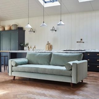 A light blue sofa in front of a large kitchen