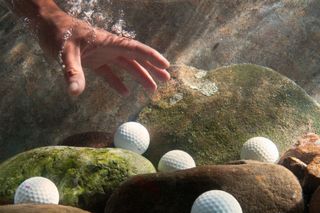 Hand fishing golf balls out of water GettyImages-104675928