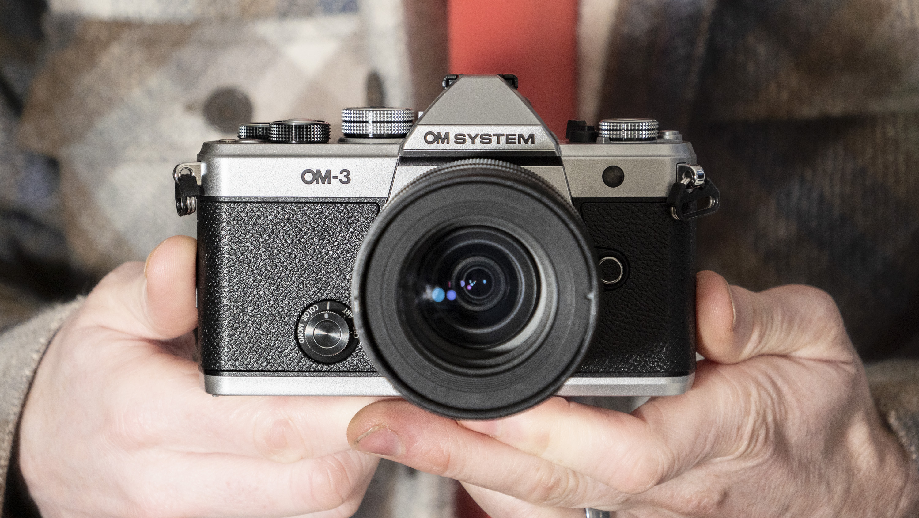 OM System OM-3 mirrorless camera in the hand, 12-45mm F4 lens attached