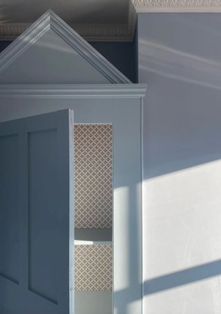 Light blue painted corner of a room. A closet door is ajar and there is a cabinet hat on top of the closet