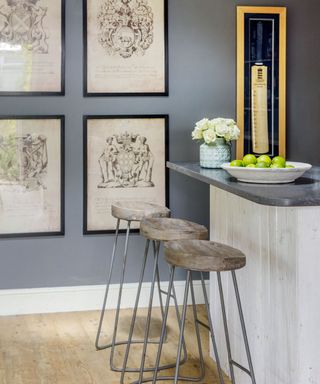Grey bar area with grey bar counter and bar stools next to wall with hanging pictures