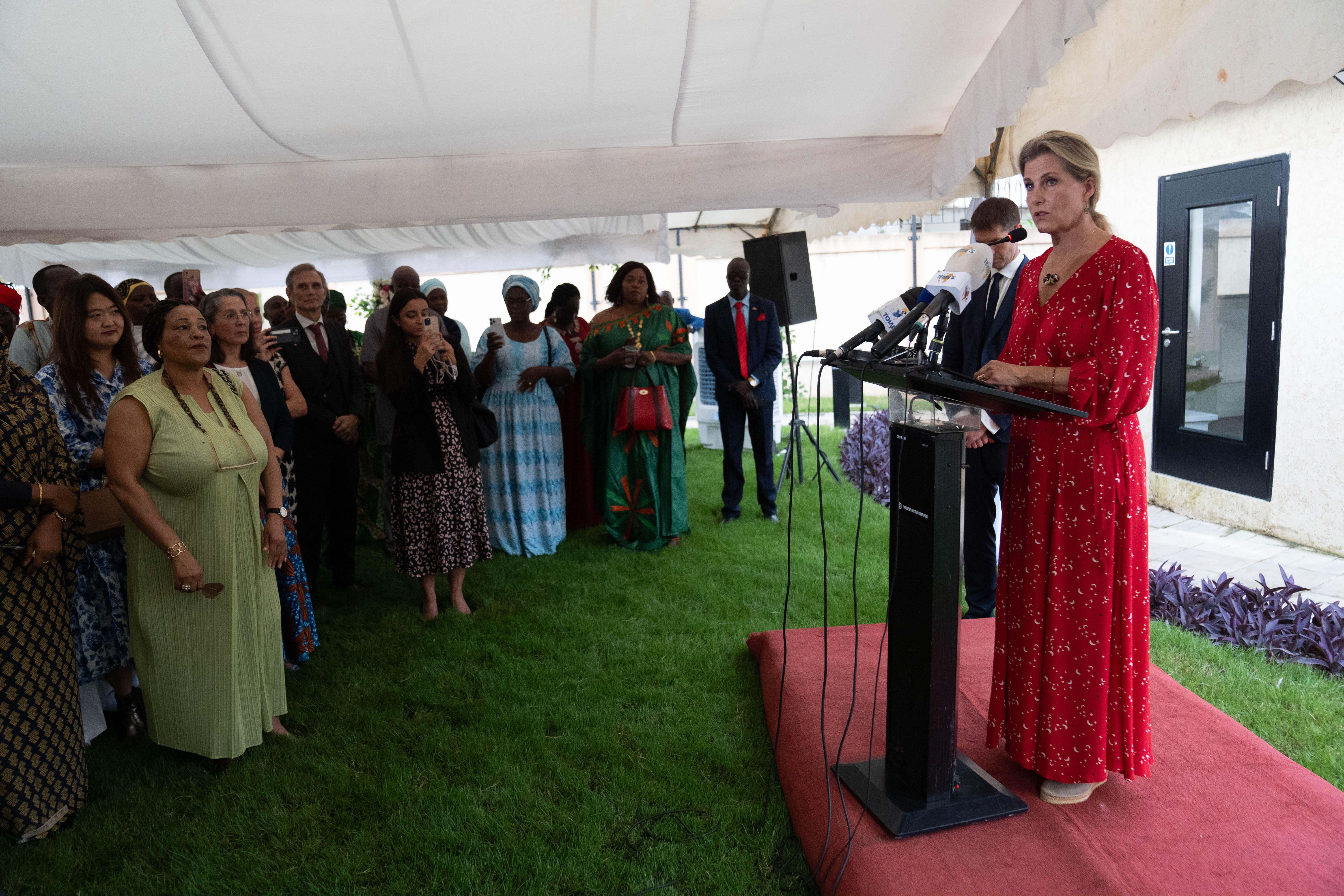 Duchess Sophie wearing a red dress standing on a podium speaking in Sudan
