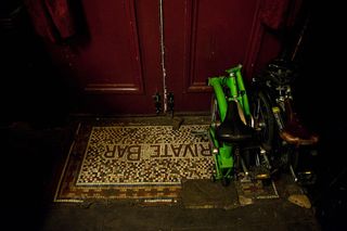 A door mat at a door with 2 folded bicycles placed on the right