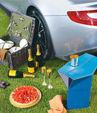 Aston Martin pictured alongside picnic hamper, strawberries and cream tart, and Veuve Clicquot champaign