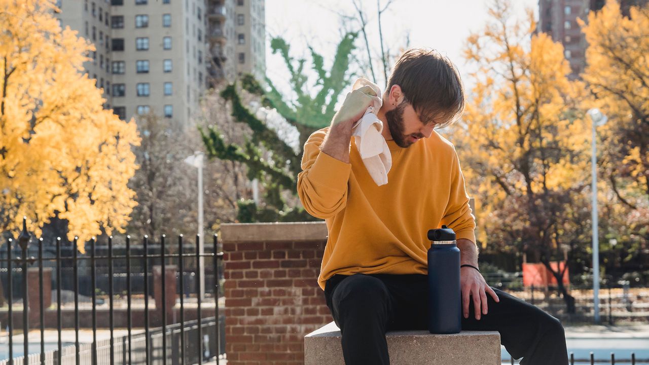 Man sitting on a ledge drying himself with a towel