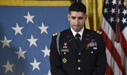 U.S. Army Capt. Florent Groberg listens to President Obama describe his heroism.