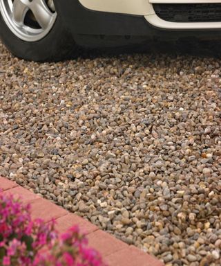 Gravel driveway with flower bed and car front