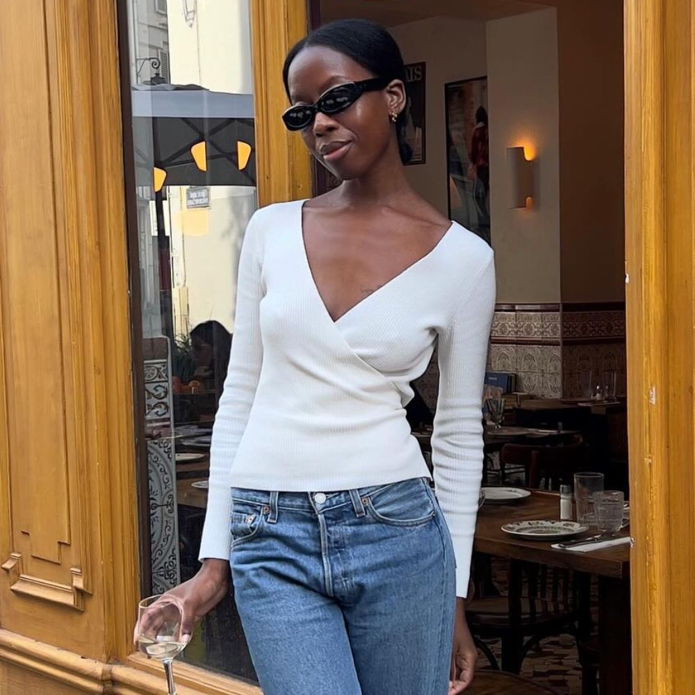 Influencer @sylviemus_ wears a white wrap cardigan with cigarette jeans and black mules.