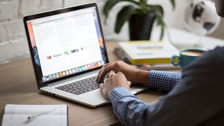 man typing on MacBook and visiting website