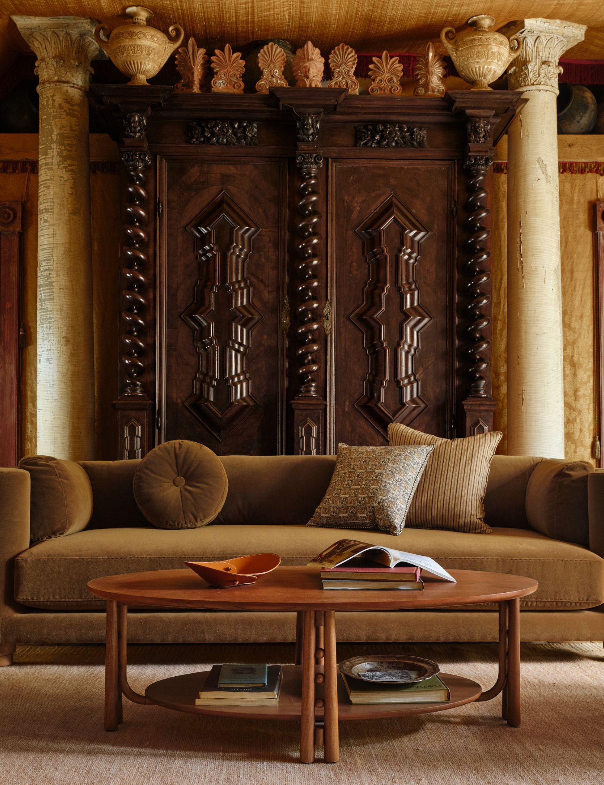 Rolled arm sofa in moss green by Pierce &amp;amp; Ward for West Elm, pictured in a Tudor-style living room with elaborate wood paneling and twin marble posts.