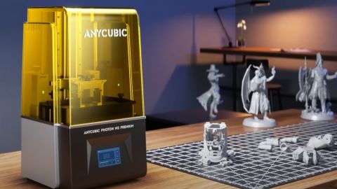 An Anycubic Photon M3 Premium on a desk, beside prints