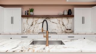 marble worktop and splashback with inset sink and copper tap