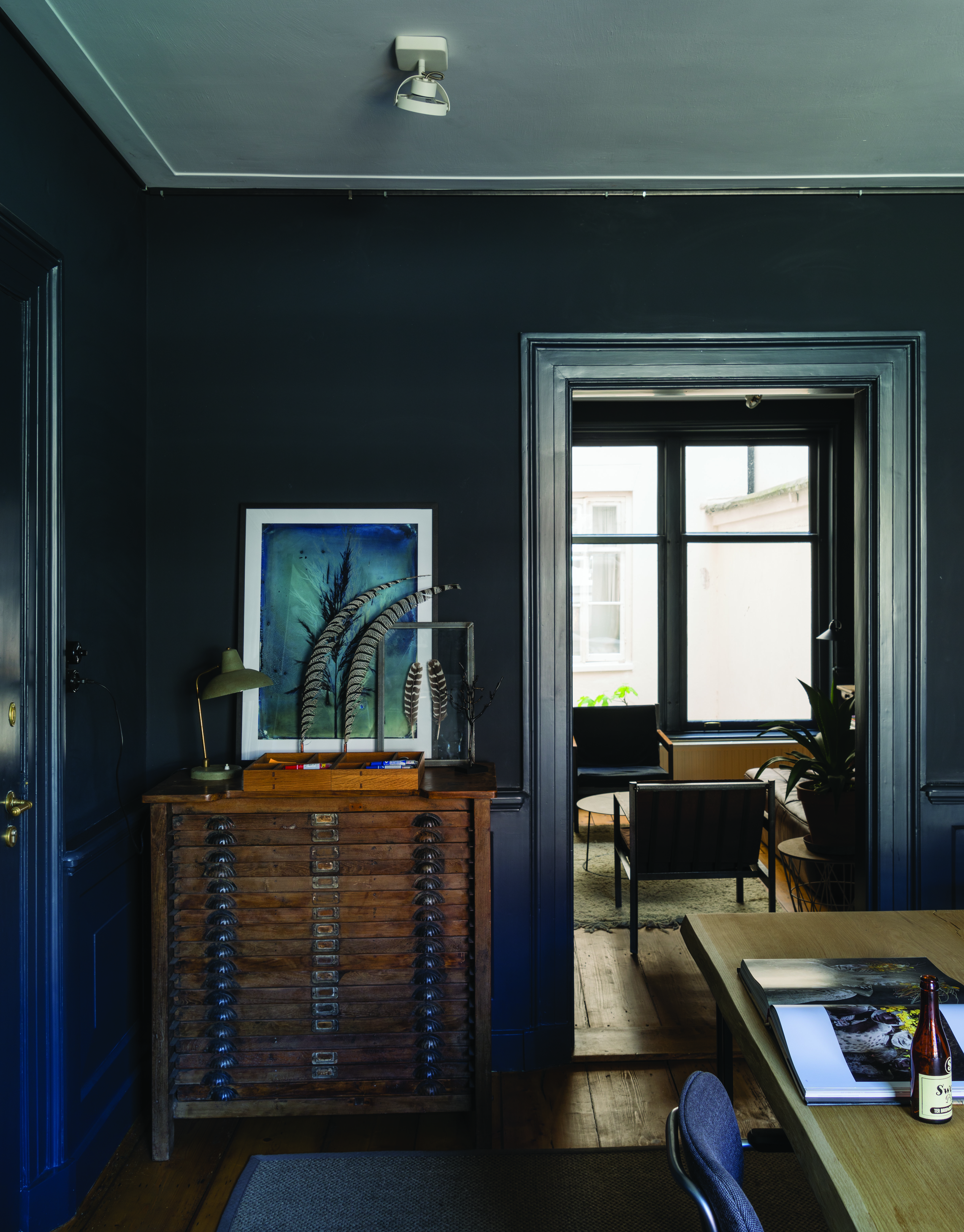 Dark living room color schemes illustrated by dark blue walls and wooden furniture.