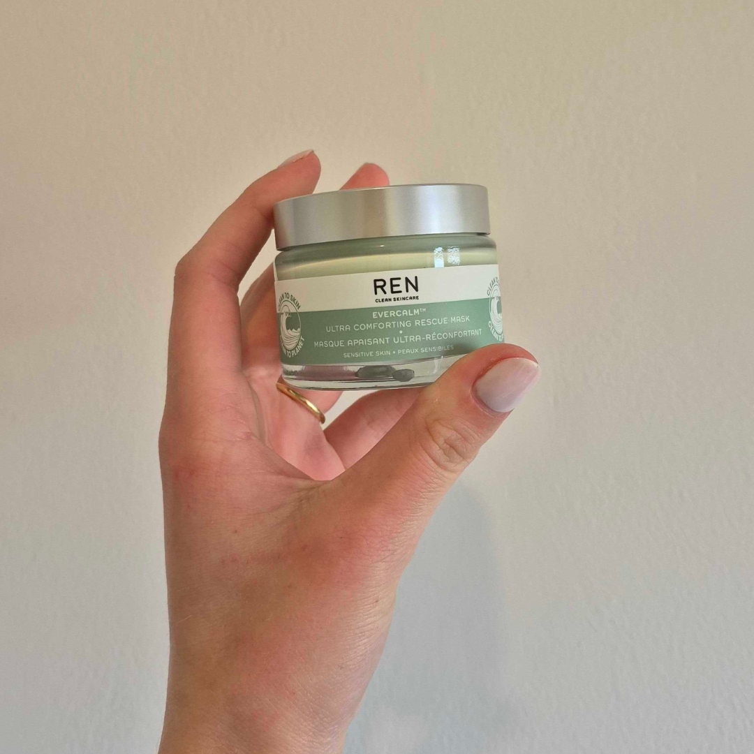 A close-up of Digital Beauty Writer, Naomi Jamieson holding up the REN Evercalm™ Ultra Comforting Rescue Mask, in front of a cream wall