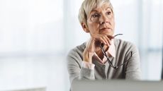 Pensive senior woman thinking while working on laptop in the office 