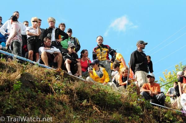 Fans atop a ridge watch the riders descending below