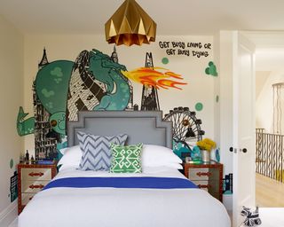 A graffiti-style mural depicting the London skyline and a fire-breathing dragon behind a bed in a teenager's bedroom.