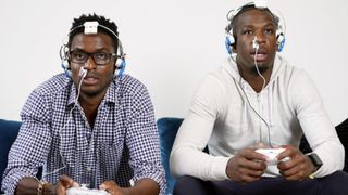 Two gamers stare intently past the camera, controllers in hand, with light therapy kits strapped to their nostrils.