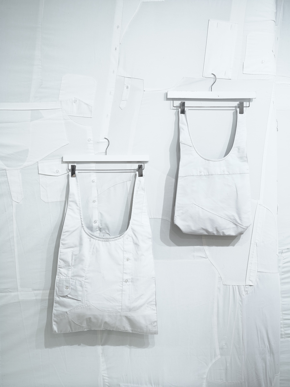 White totes hanging on wall of stitched-together white shirts