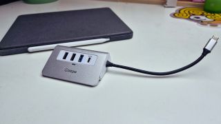 A USB-C hub on a desk with an iPad in the background