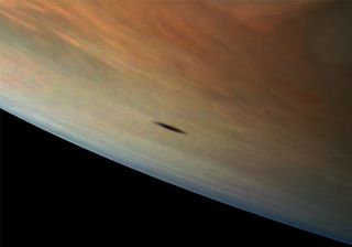Amalthea, the largest of Jupiter's inner satellites, casts a shadow on the giant gas planet in this photo taken by NASA's Juno spacecraft. The moon's shadow has an elongated shape because of its position in relation to Jupiter, but also because the moon itself has an odd shape. Because Jupiter has at least 69 moons, solar eclipses like this one are more common than they are here on Earth.