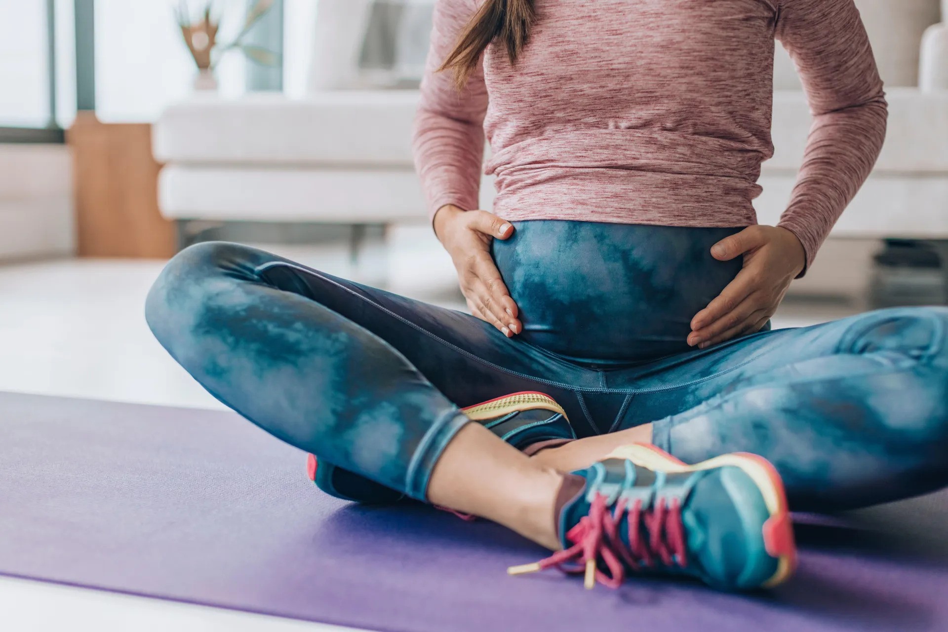 Pregnant woman holding her stomach on an exercise mat