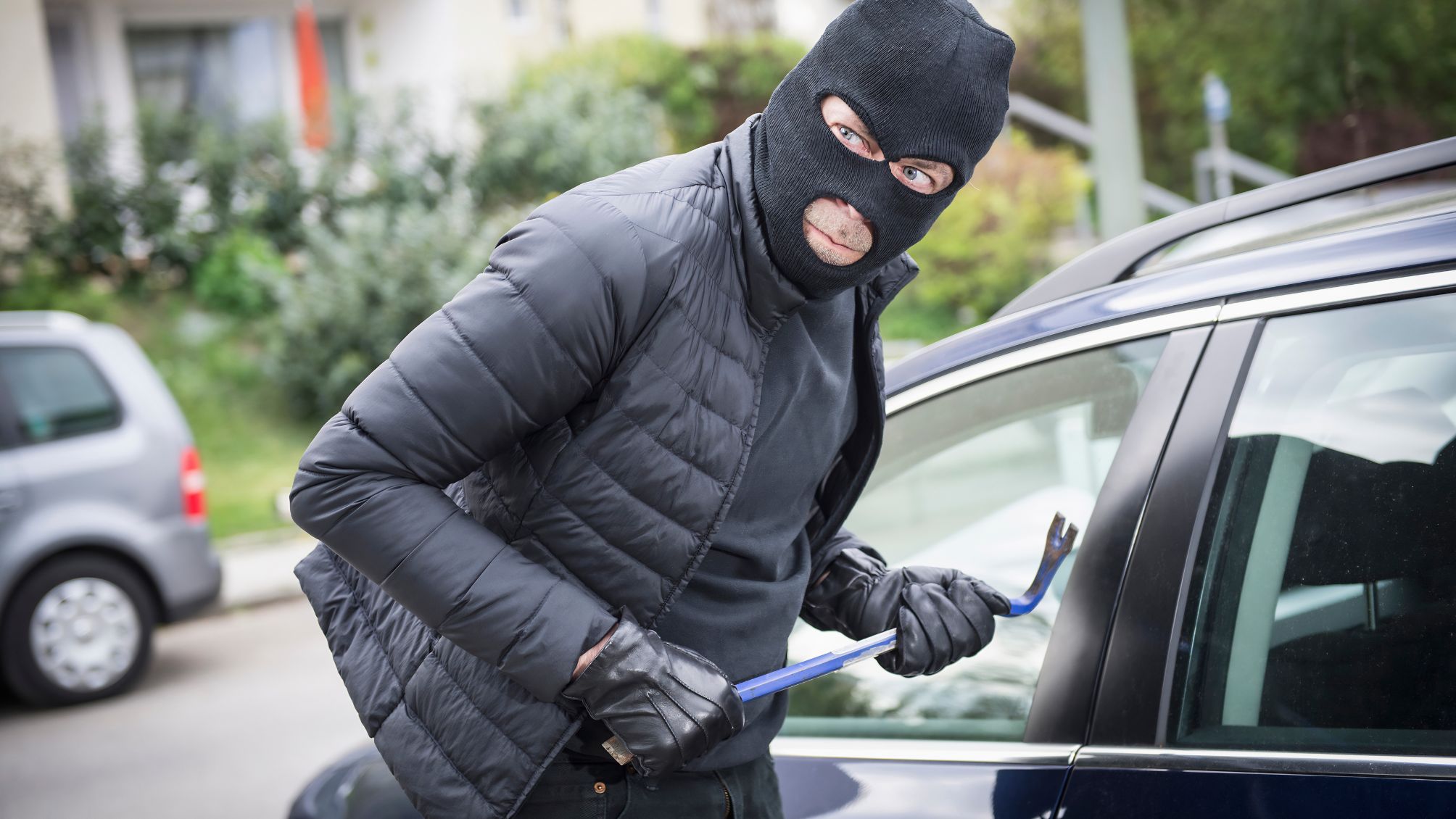 A thief looking around before breaking into a car