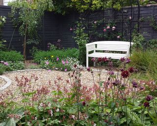 round gravel patio with white painted wooden garden bench