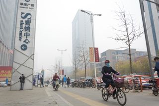 A cyclist rides through smog in Shenyang.