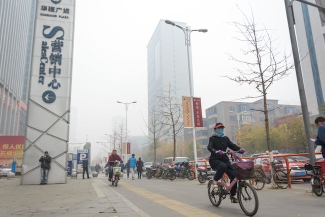 A cyclist rides through smog in Shenyang.