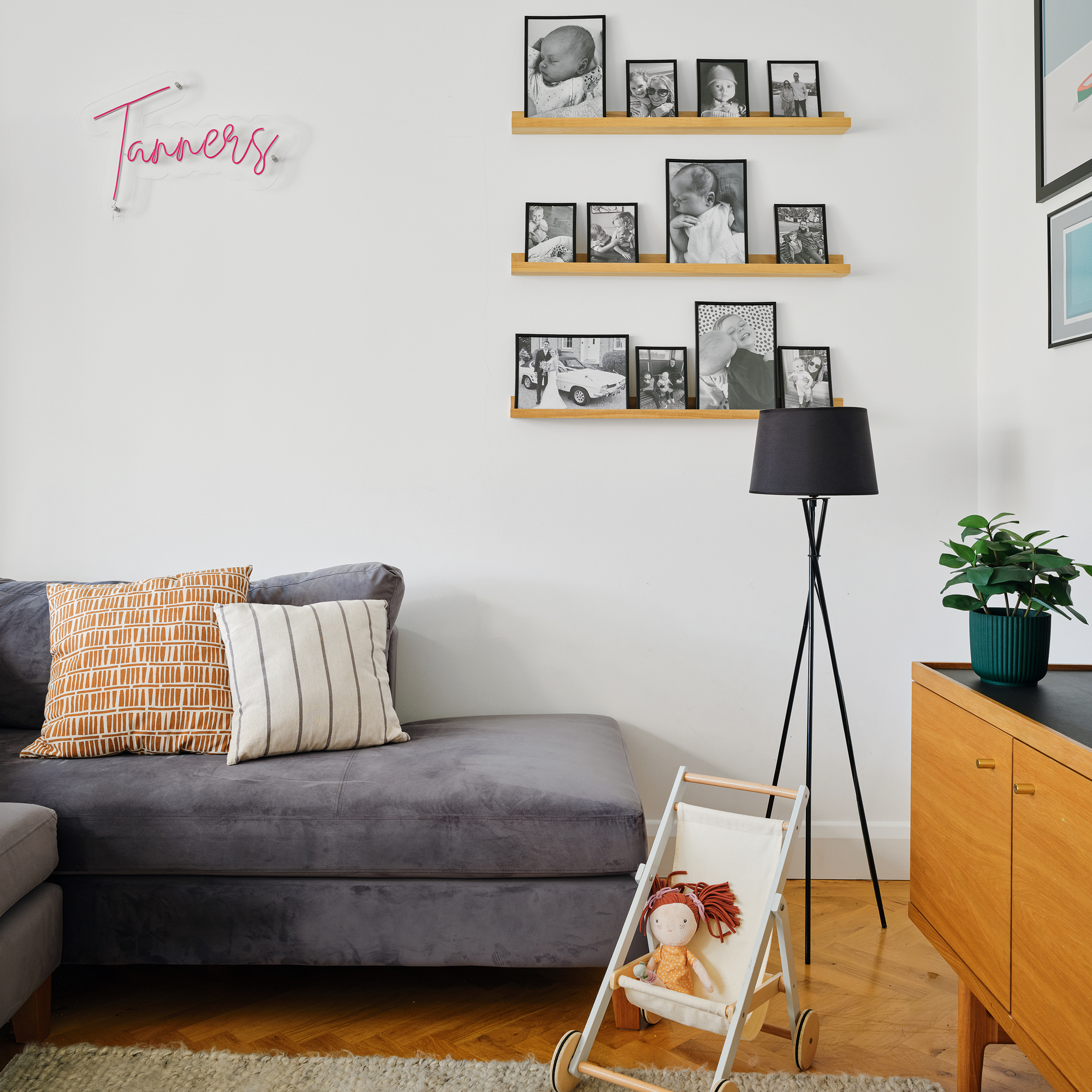 a seating area with sofa, framed photographs on the wall and a mid century sideboard