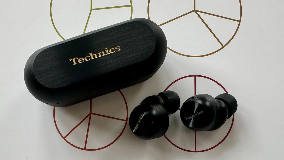 A pair of Technics EAH-AZ100 earbuds on a white desk