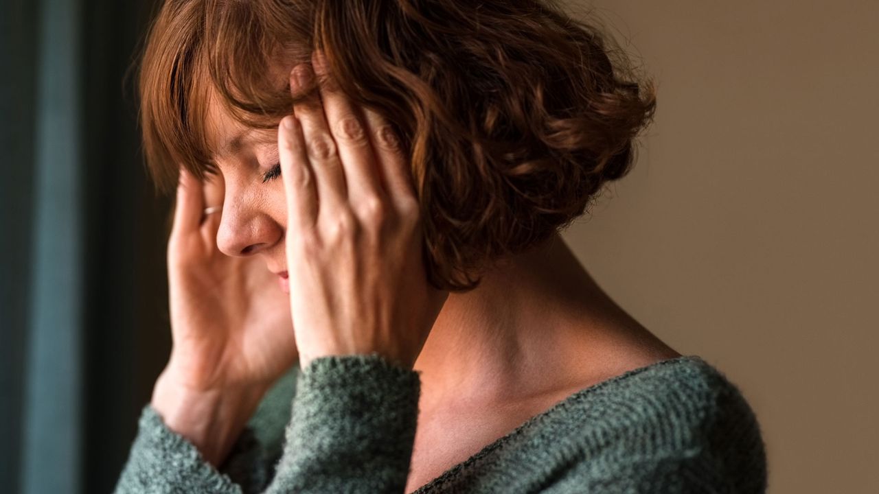 Woman with hands on either side of her head.