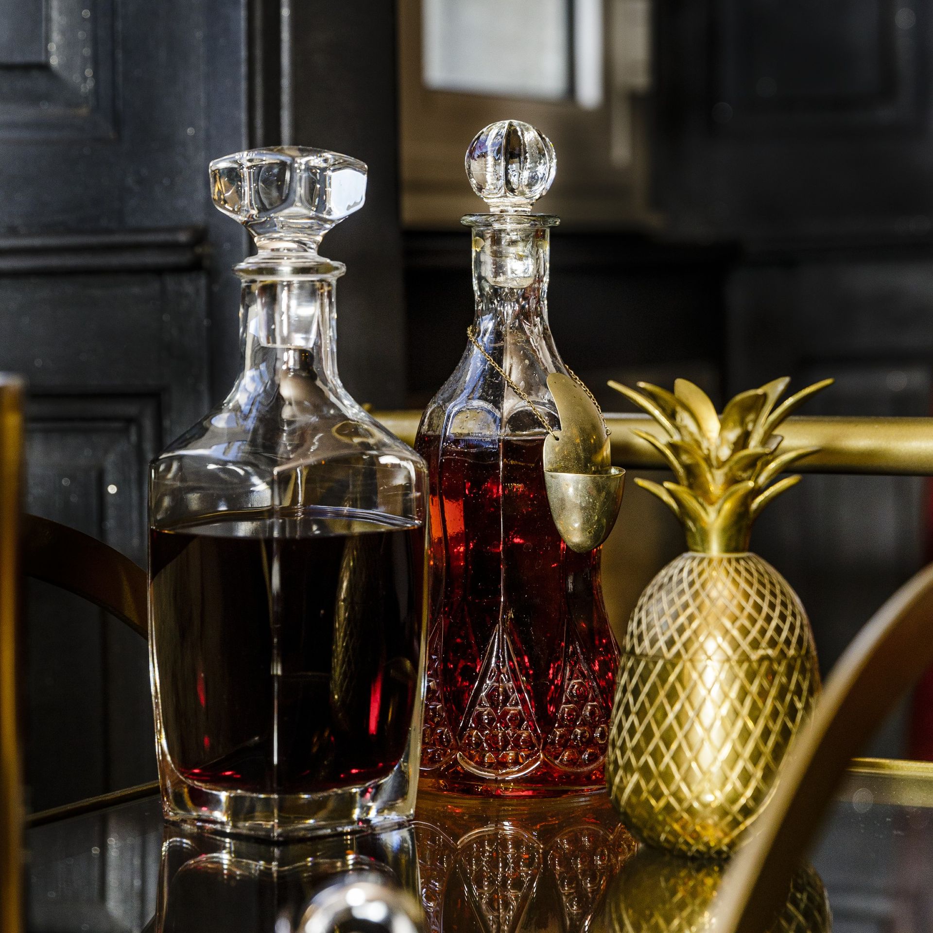 Glass decanter and bottles on top of gold bar cart